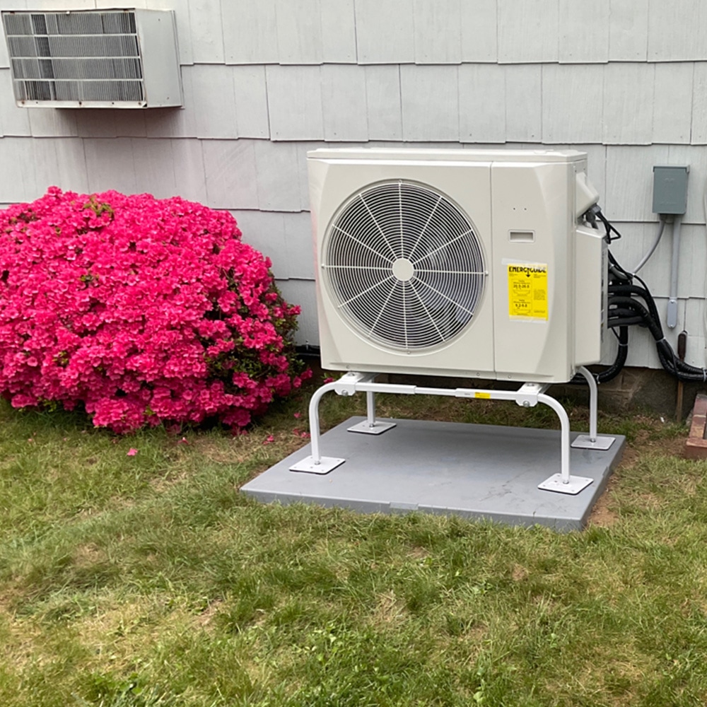Newly installed heat pump next to a vibrant flower bush